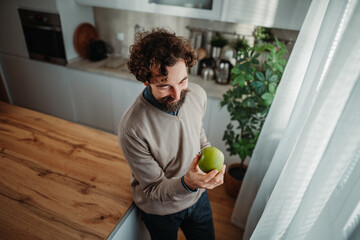 Fototapeta premium Man holding green apple thinking about healthy eating