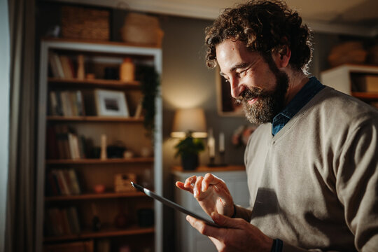 Smiling man using digital tablet at home - Powered by Adobe