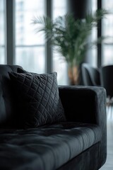 Fototapeta premium Dark velvet sofa with a quilted cushion in a modern living room, large windows and a blurred plant in the background. Concept Dark velvet sofa, Quilted cushion detail, Modern living room