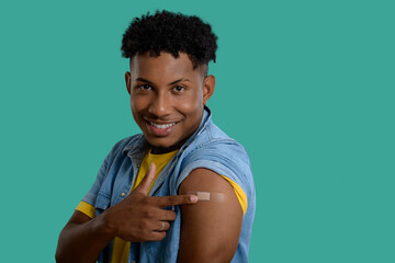 Young man proudly displays his post-vaccination bandage.