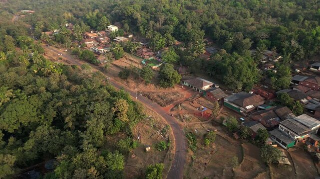 Beautiful ariel crane down view of village road and greenery 