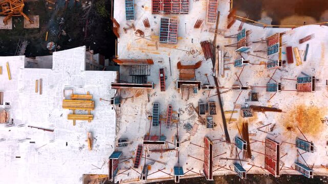 Workers are busy at a construction site where a large structure is being built. Various materials like wooden planks and metal beams are scattered around.