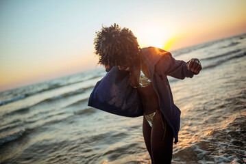Carefree woman dancing at beach during golden hour sunset