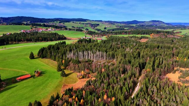 A wide view shows fields of green grass and patches of trees under a clear blue sky.