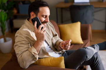 Man making phone call holding credit card at home