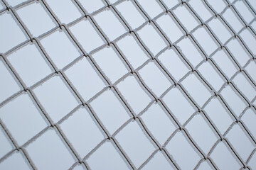 a chain-link fence covered in ice crystals on a cold winter day