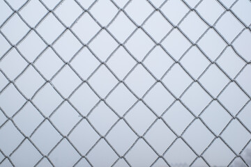 Fototapeta premium a chain-link fence covered in ice crystals on a cold winter day