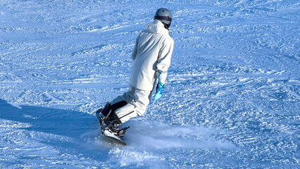 Snowboarder is riding down a snowy slope