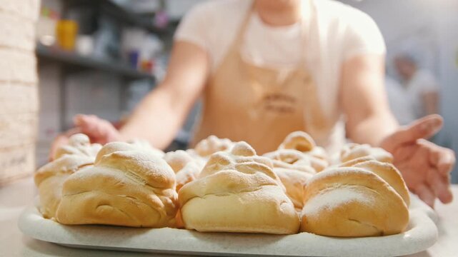 Cook carrying the fresh hot buns in the bakery