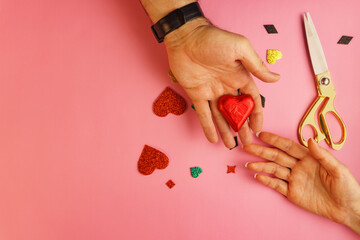 Man giving chocolate heart to woman on pink background with golden scissors and copy space.