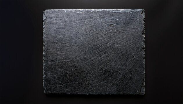 a square piece of dark grey slate stone with a naturally rough and textured surface shown from above on a black background
