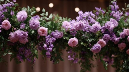 Fototapeta premium Close-up of a beautiful floral arrangement hanging from a wooden ceiling. the arrangement is made up of multiple layers of pink and purple flowers, with green leaves and stems.