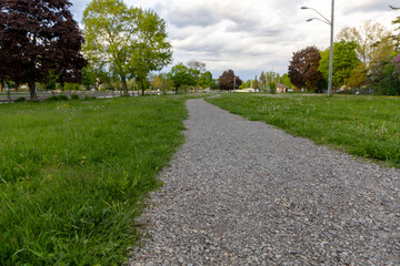Walking path through green grassy park in Smiths Falls, Ontario, Canada. Long trail for hiking and recreation in public parkland.