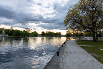 Sunset over Rideau river with cloudy sky. Peaceful evening view of waterway and park in Smiths Falls