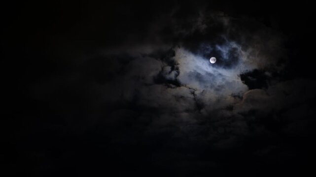 Clouds passing in front of the moon at night