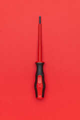 Obraz premium Red Screwdriver on Red Background: Minimalist Tool Design for Creative Projects