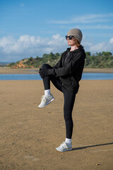 sporty woman doing leg stretching exercise at the beach