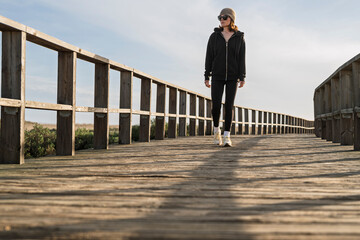 sporty woman walking on a wooden boardwalk