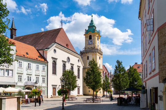 Visitors and locals alike enjoy a sunny day in Bratislava's historic Main Square (Hlavn&eacute; n&aacute;mestie), which is anchored by the iconic yellow Old Town Hall tower and the white Jesuit Church.