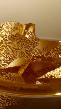 Vertical video: Shifting camera revealing gold filigree on shallow dish, showing warm sheen