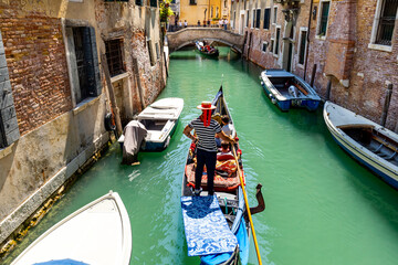 Gondolier on a narrow canal in Venice, Italy
