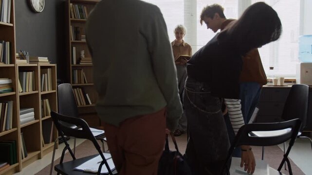 Group of teenage students with backpacks entering college counsellor office then sitting down on chairs to fill out mental health questionnaires