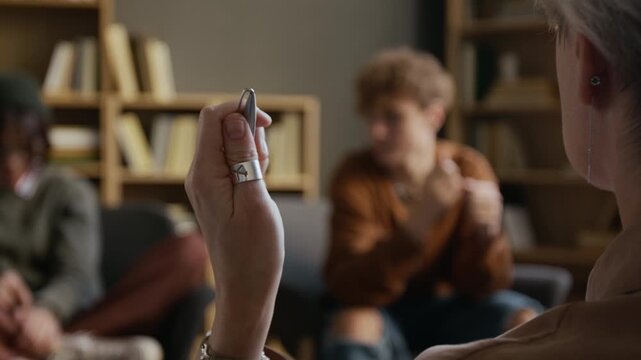 Selective focus on hand of female psychotherapist listening to teenage boy opening up about feelings during couple therapy with girlfriend in counseling office