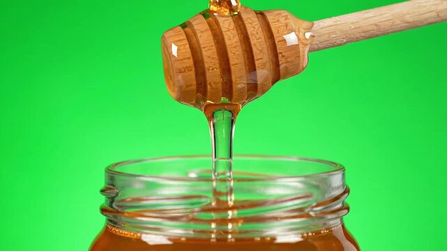 Honey dripping from honey dipper on green screen