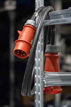 A 400 V five‑pin extension cable, coiled and hanging on a shelf.
