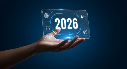Hand holding transparent screen with 2026 and icons on blue background