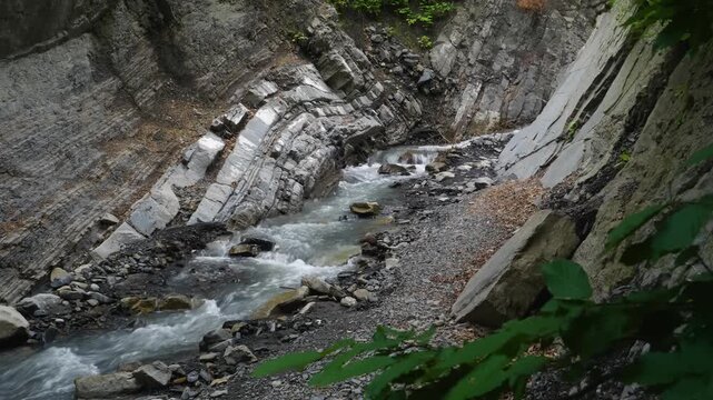 Scenic view of the Prut river flowing through the Yaremche folds, a significant geological outcrop of the Stryi formation in Europe. The rocks display striking gothic or chevron type folds and faults.