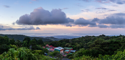 View west from Monteverde resort at sunrise over the hills towards Pacific ocean in broad panoramic format