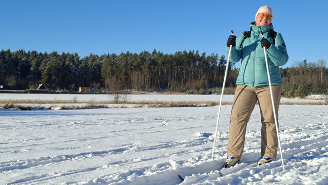 Mature woman skiing on trail in winter cold weather. Cross-country skier in snowy National park Sumava, Czech Republic.