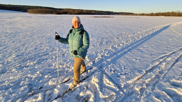 Mature woman skiing on trail in winter cold weather. Cross-country skier in snowy National park Sumava, Czech Republic.