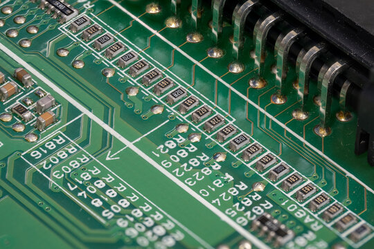 A macro detail of a resistor on a green printed circuit board.
