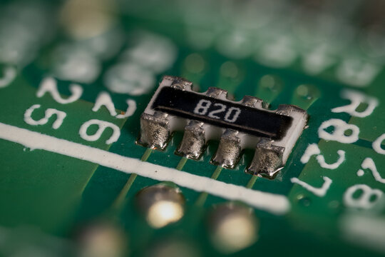 A macro detail of a resistor on a green printed circuit board.

