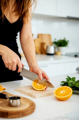 Woman cutting an orange in the kitchen