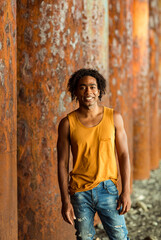 A young handsome man,an African model, walks alone, in a yellow T-shirt and jeans, in an unusual place