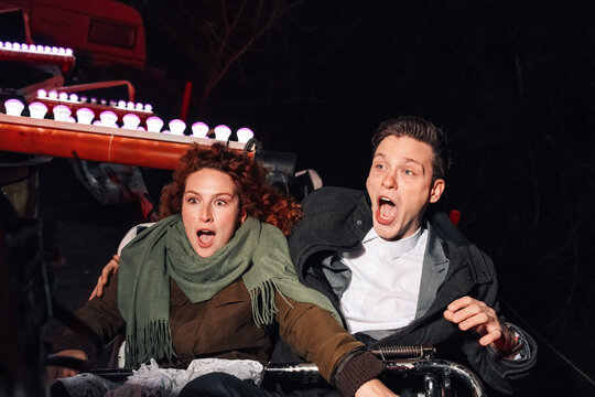 Couple screaming on fairground ride at night