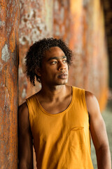 A young handsome man,an African model, walks alone, in a yellow T-shirt and jeans, in an unusual place