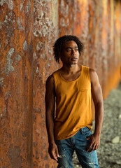 A young handsome man,an African model, walks alone, in a yellow T-shirt and jeans, in an unusual place