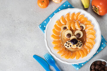 Breakfast food art of kids - Lion pancake with tangerines, banana and chocolate on white plate, Copy space
