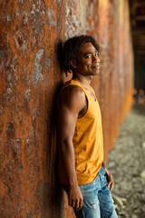 A young handsome man,an African model, walks alone, in a yellow T-shirt and jeans, in an unusual place