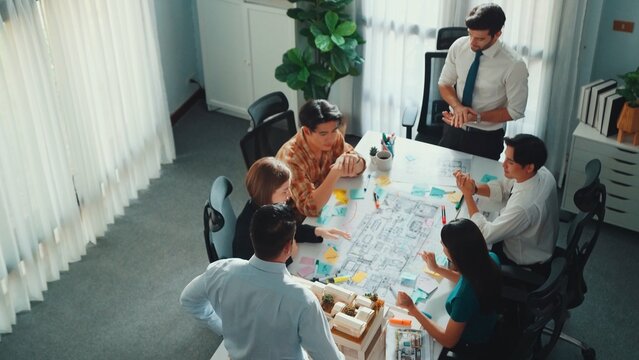 Group of diverse team planning strategy while sitting at table with project plan. Top aerial view of smart business people working together to brainstorm and design house construction. Alimentation. - Powered by Adobe
