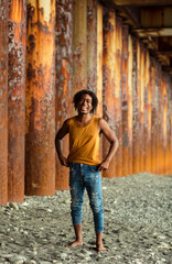 A young handsome man,an African model, walks alone, in a yellow T-shirt and jeans, in an unusual place
