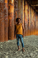 A young handsome man,an African model, walks alone, in a yellow T-shirt and jeans, in an unusual place