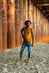 A young handsome man,an African model, walks alone, in a yellow T-shirt and jeans, in an unusual place