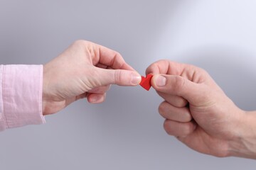People with red decorative heart on light grey background, closeup