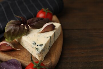 Dairy product. Piece of cheese, tomatoes, basil and garlic on wooden table, closeup. Space for text