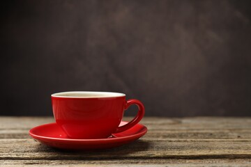 Cup with aromatic coffee on wooden table against dark background, closeup. Space for text